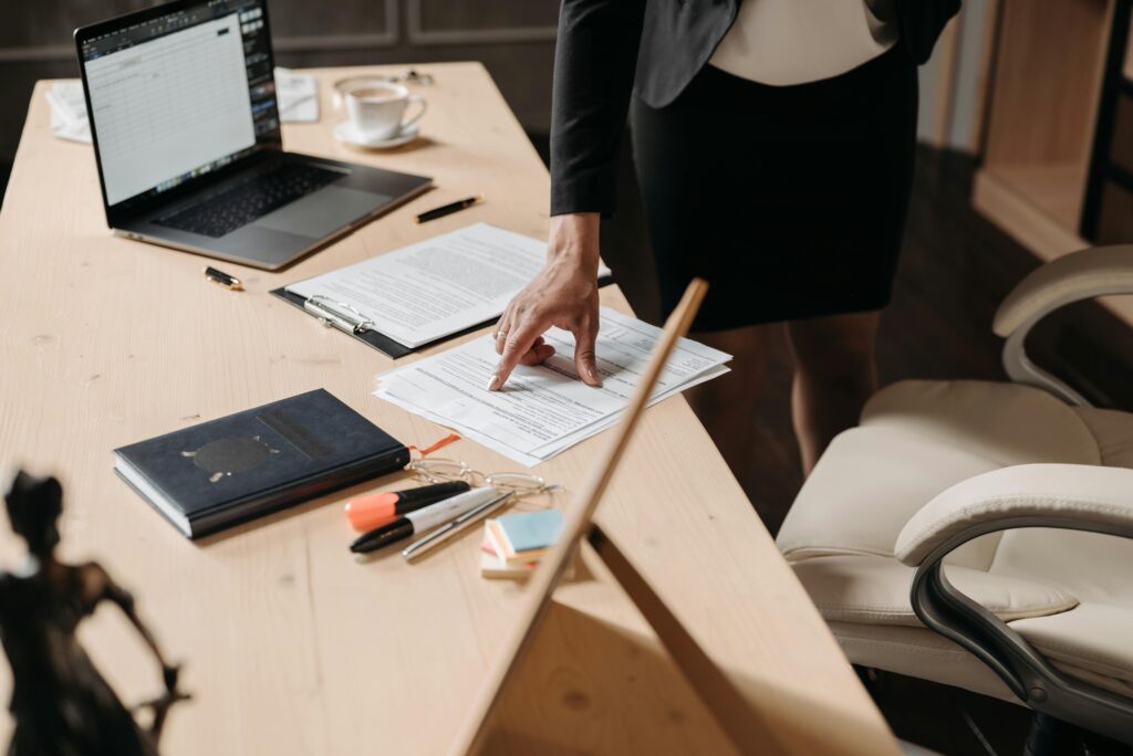 Businesswoman pointing at paperwork on a desk in an office setting, highlighting key data.